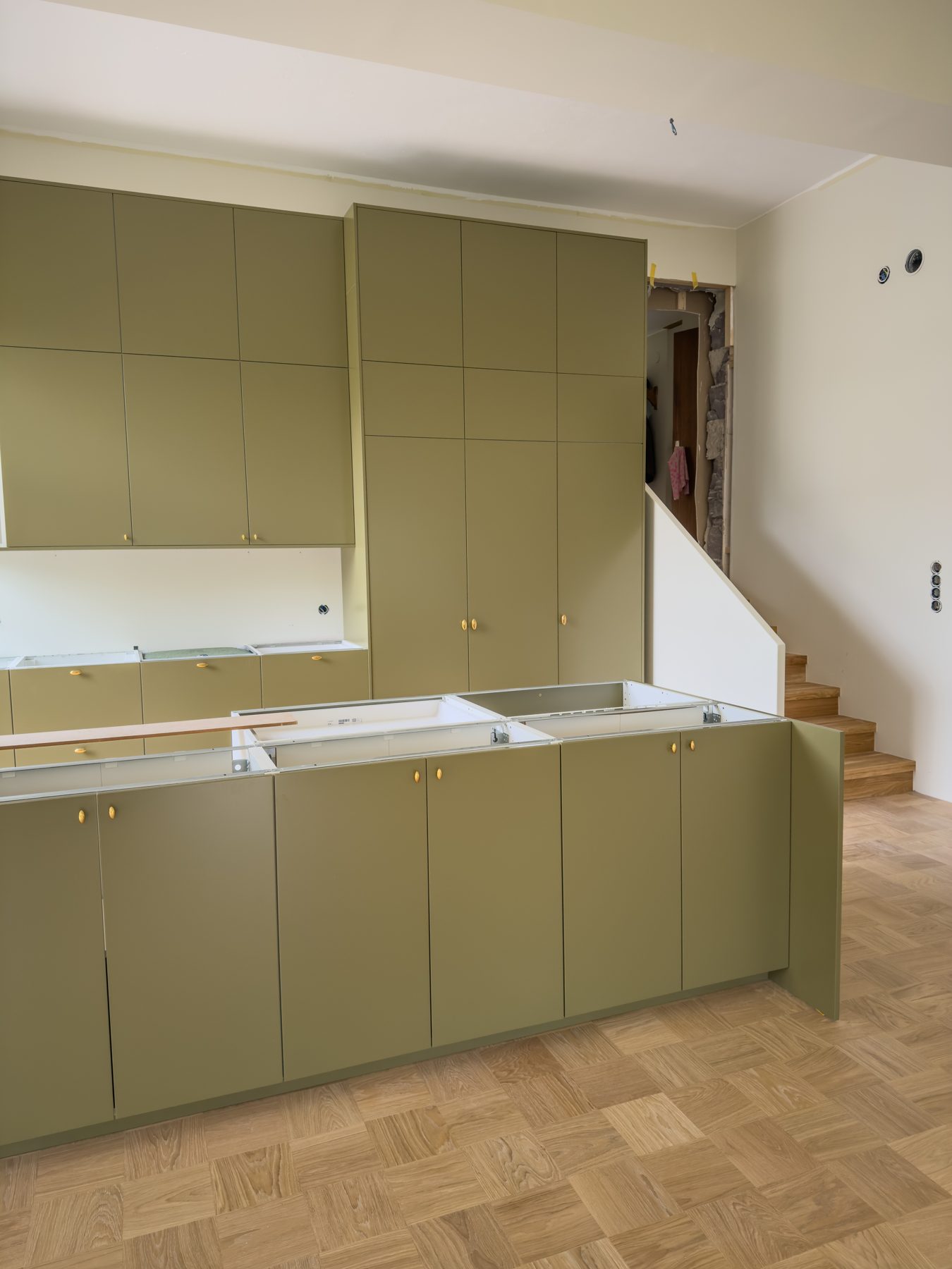 Pågående totalrenovering med platsbyggt olivgrönt kök i Stockholm